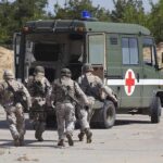 Soldiers running towards a medical vehicle during a military operation