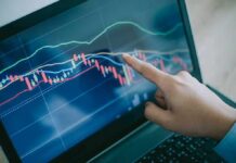 Hand pointing at stock chart on laptop screen