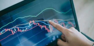 Hand pointing at stock chart on laptop screen