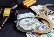 Gavel, handcuffs, and cash on a dark table