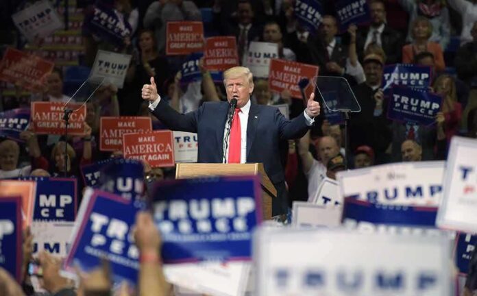 shutterstock_1427778638 Donald Trump speaks at a rally, giving two thumbs up