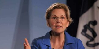 Elizabeth Warren speaking at an event with a flag in the background