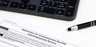 Unemployment benefits application form with keyboard and pen