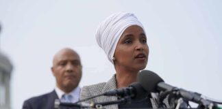 1 Missing Record Could Unravel Ilhan Omar’s CITIZENSHIP Ilhan Omar speaking at a podium with André Carson standing behind