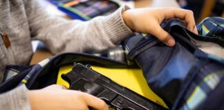 hand reaches into backpack with a handgun inside