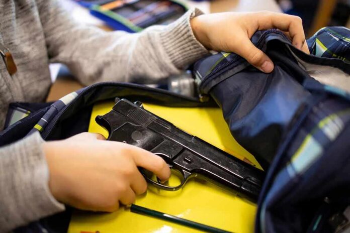 hand reaches into backpack with a handgun inside