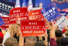Crowd holding red and blue campaign signs at a political rally