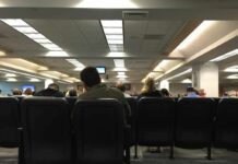 People seated in a waiting room with rows of chairs