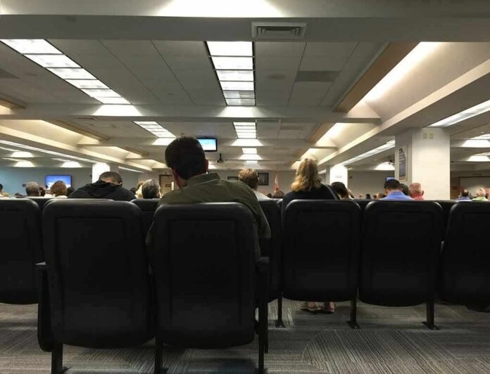 People seated in a waiting room with rows of chairs