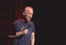 Bill Maher performing stand-up with a microphone on stage